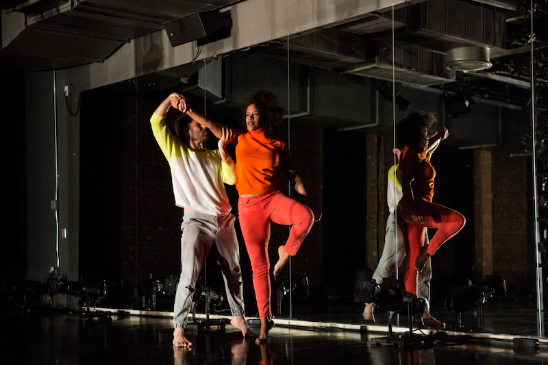 Darrin Wright holds Leslie Cuyjet's outstretched right arm as she balances on one leg in front of a mirror.